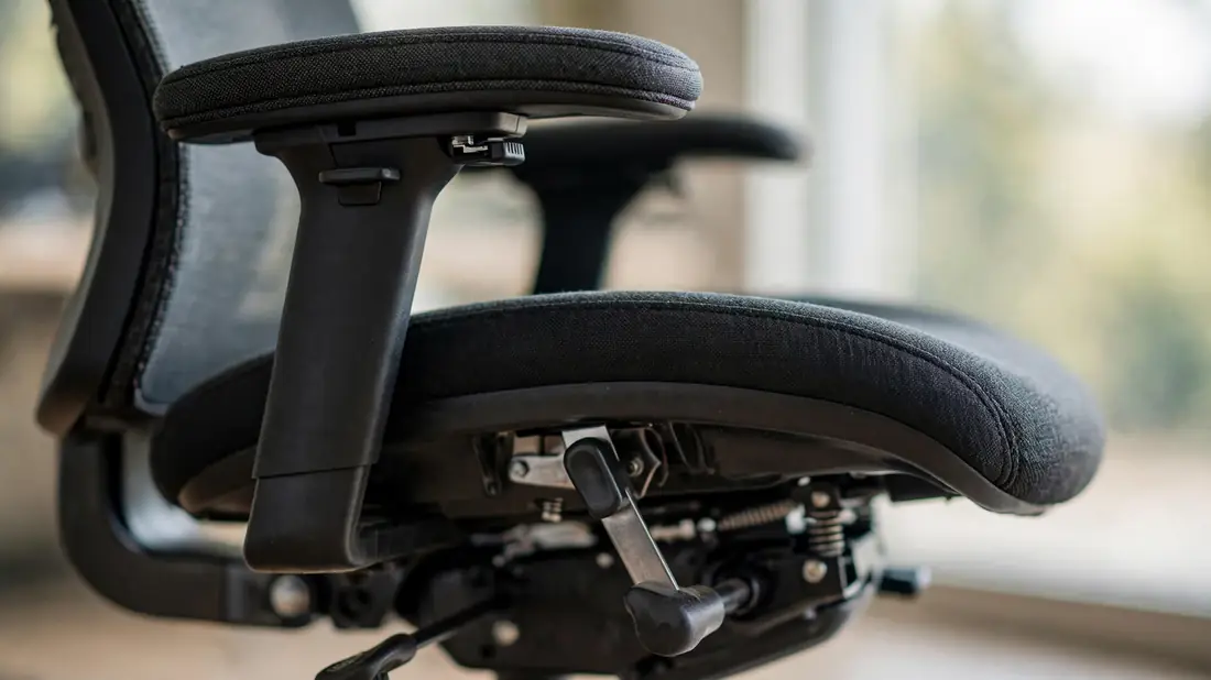 Close-up of an office chair's adjustable armrest and seat-height lever