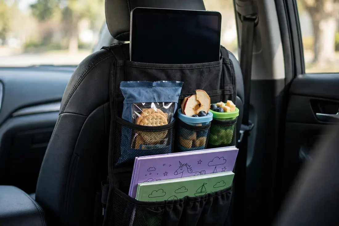 Seat-back organizer with tablet, snacks, and coloring books for kids